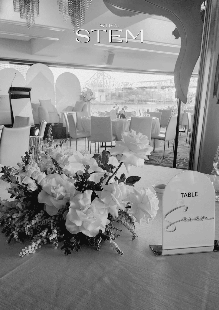 Yellow and white corporate flower arrangement on a table overlooking the Story Bridge in Brisbane.