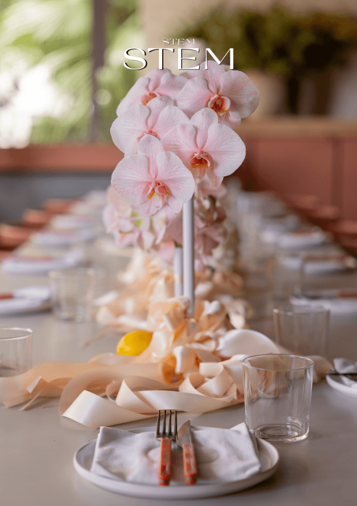 Soft pink orchid table arrangement with flowing ribbon textures created for a modern Brisbane event.
