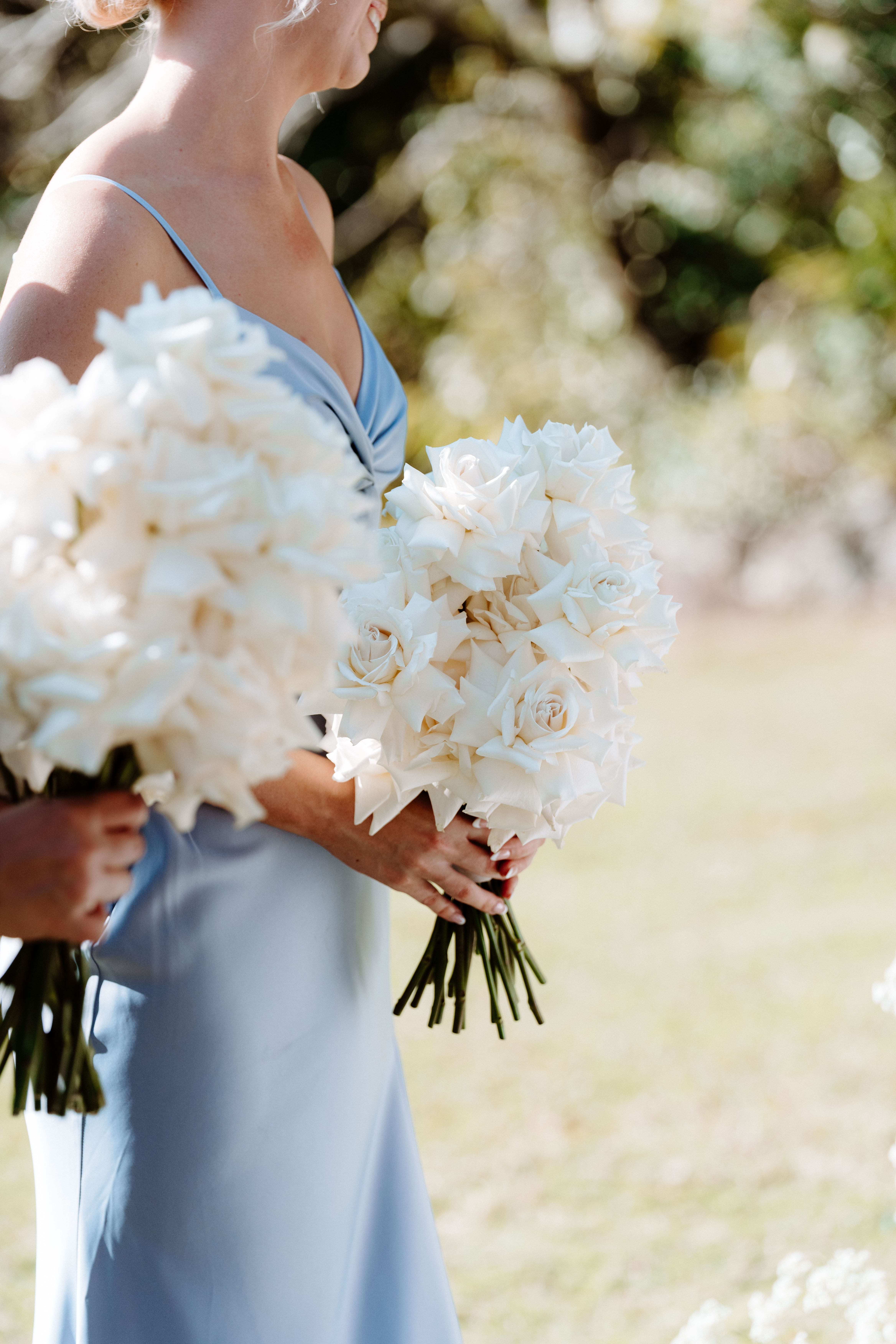 Bridesmaids holding elegant white rose bouquets designed by Stem Design for a Brisbane wedding.