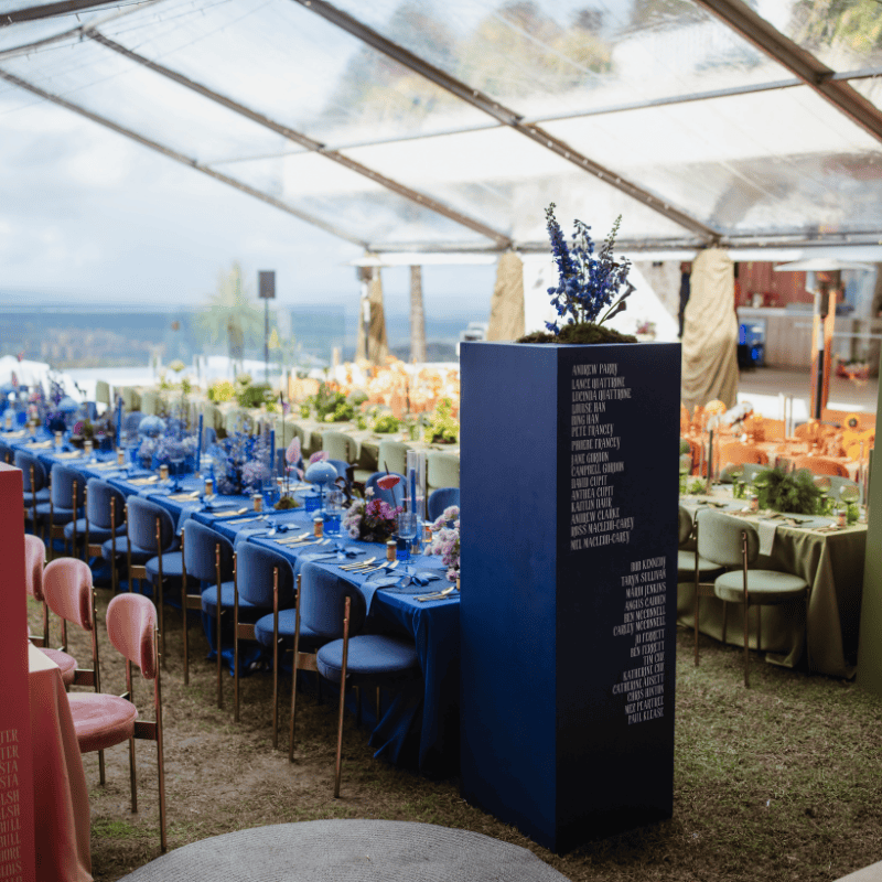 Blue wedding reception flowers under a clear marquee