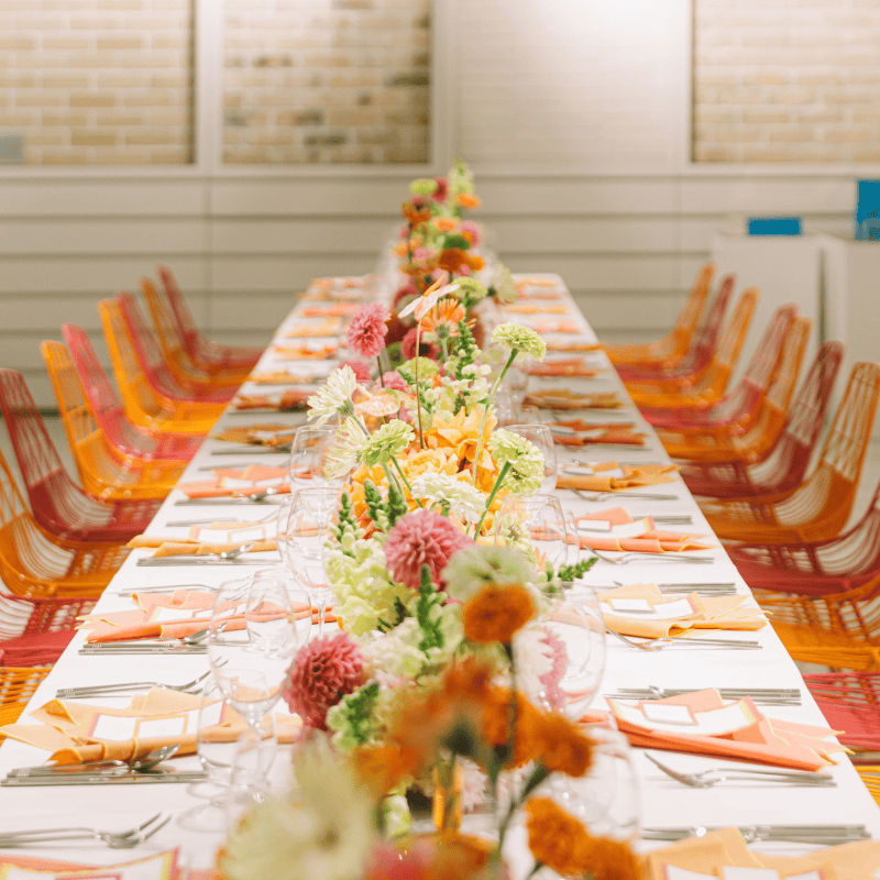 Long event table with colourful flowers and orange styling in Brisbane